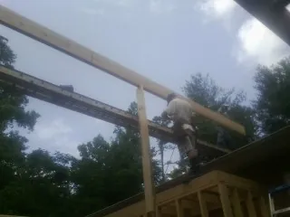 Carpenter setting a ridge beam over a new addition frame — Ice Dam Removal by Roofing Brothers in Masury