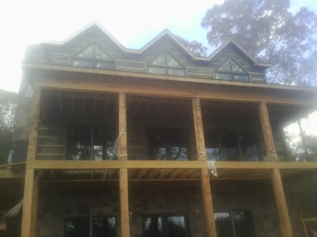 Dormers and porch framing on a large log home under construction — Roof Coating work by our crew in Masury