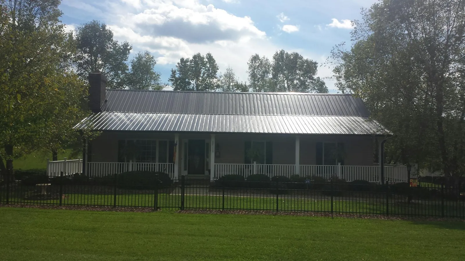 Gray metal roof on a brick ranch with a full width front porch — Gutter Guard Installation work by our crew in Masury