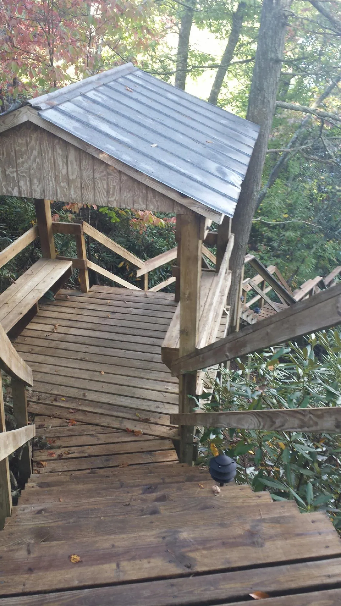 Metal roofed shelter over wooden steps on a wooded walkway — Skylight Repair & Installation work by our crew in Masury