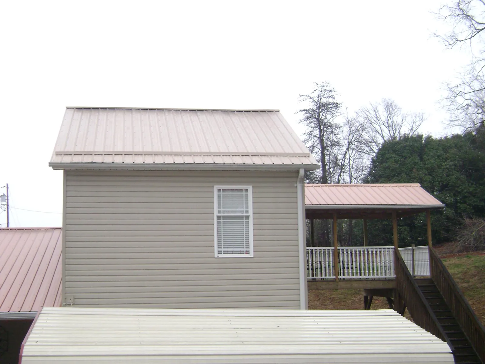 Tan metal roofs on a two story addition and attached porch, from a Roof Replacement job in Masury