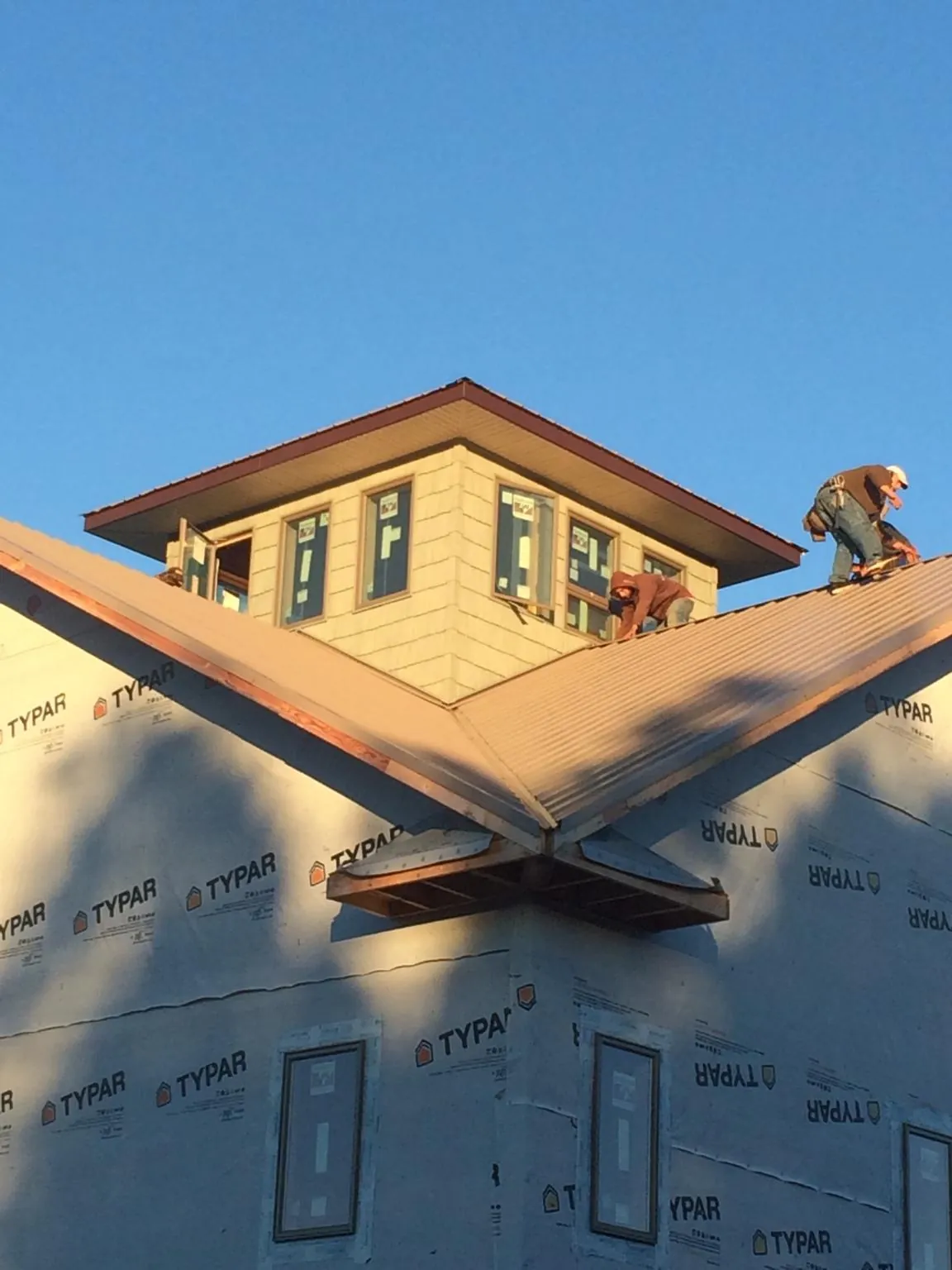 Roofers working around a rooftop cupola on a new metal roof at sunset — Roof Waterproofing in Masury by Roofing Brothers